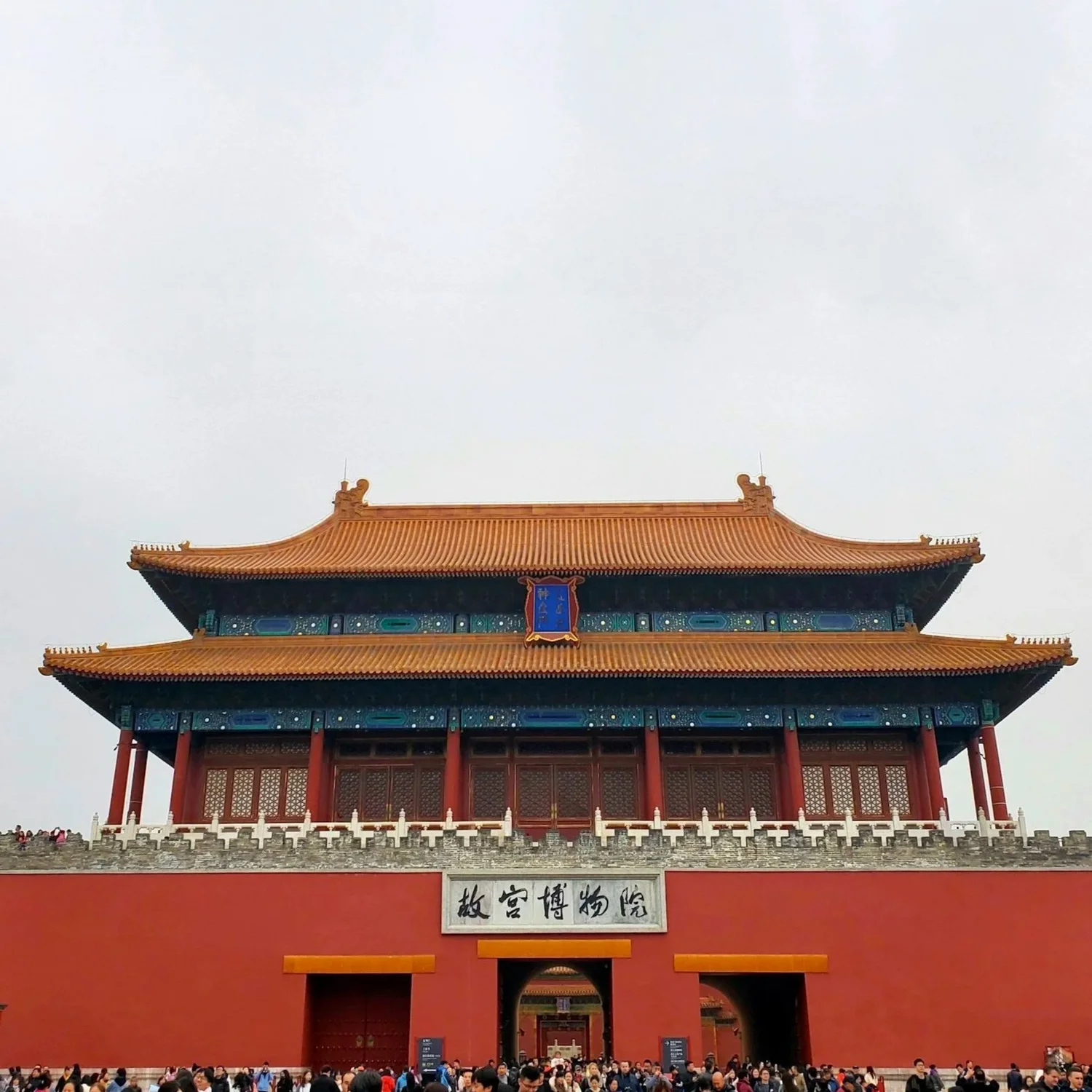 Entrance gate of the Forbidden City with a large crowd of visitors, traditional Chinese architectural features, and Chinese characters on a sign above the gate.