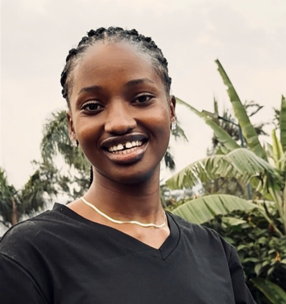 Meet Niheza Deborah, the host of Hyperlocal Sabbatical monthly stay packages around the world. A smiling woman with braided hair stands outdoors with greenery and palm trees in the background.