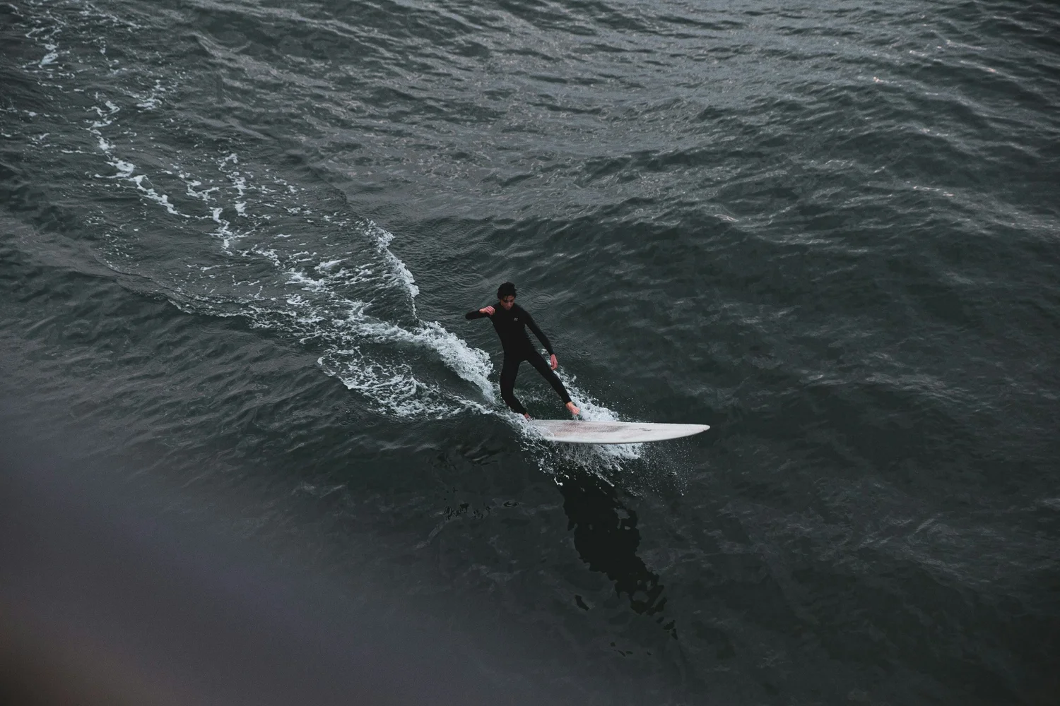 Person surfing on a wave in the ocean. Hyperlocal World of Travel.