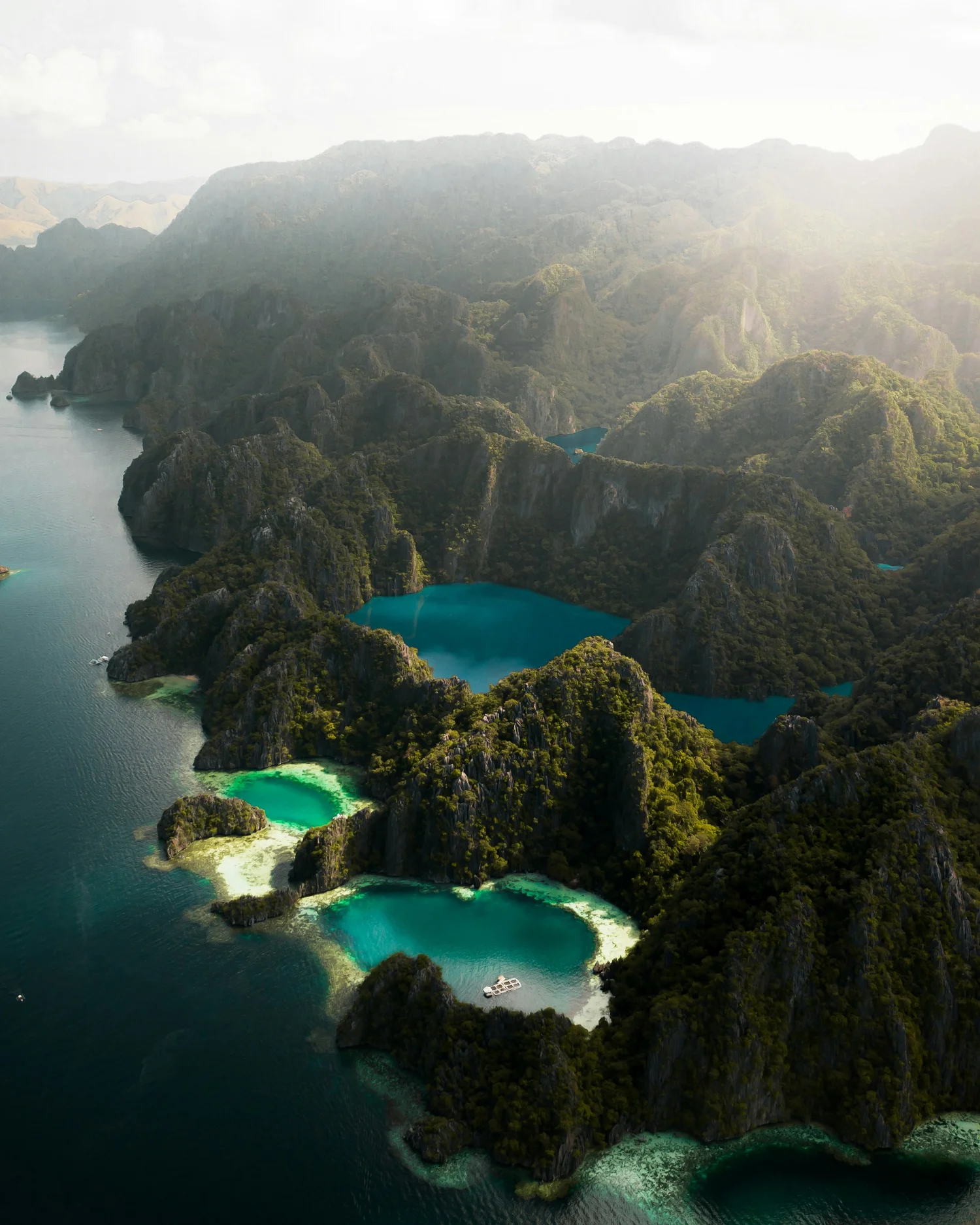 Aerial view of limestone islands with lush green vegetation and turquoise waters, located in a tropical bay.