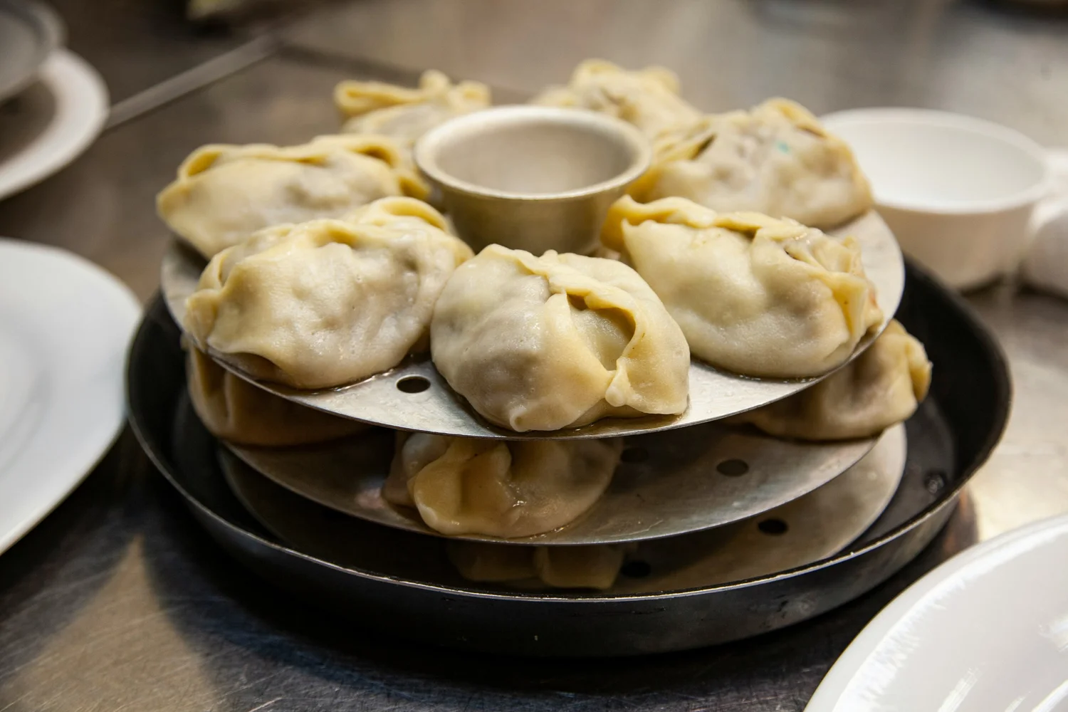 Plate of steamed dumplings with dipping sauce in the center.