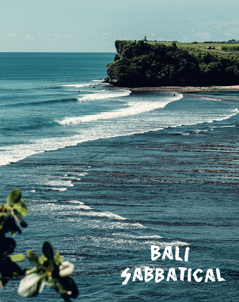 View of a coastal cliff with a grassy top and a few people walking, overlooking a beach with gentle waves, in Bali, with the text 'Bali Sabbatical' in the bottom right corner.