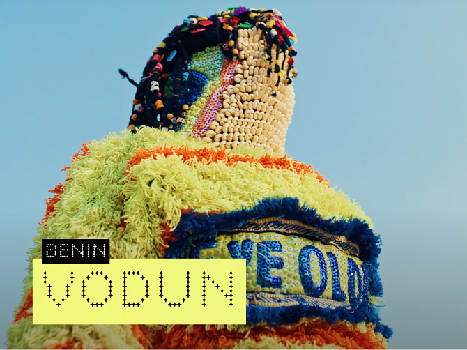 Colorful garment made of various textured fabrics and beads, with a label reading 'Benin' and 'VODOUN'. Hyperlocal World of Travel.