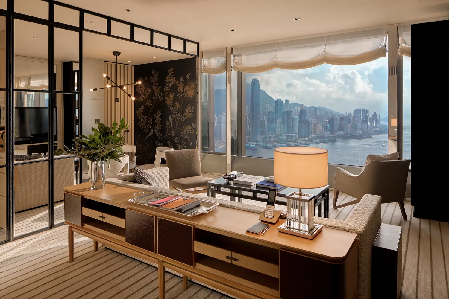 Luxury hotel suite with panoramic city view, modern furniture, and decorative lighting.